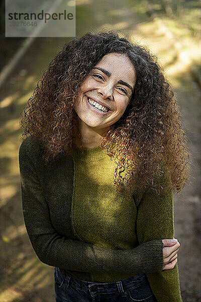 Happy woman with curly hair standing at park