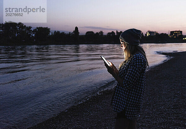 Frau benutzt Smartphone in der Abenddämmerung