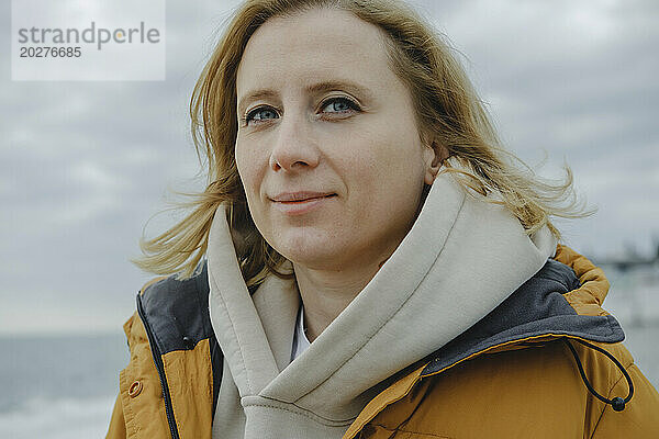 Blonde Frau unter Himmel am Strand