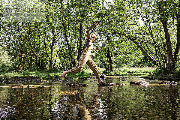 Frau springt auf Felsen im Flusswasser