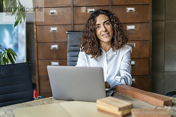 Geschäftsfrau sitzt mit Laptop im Büro