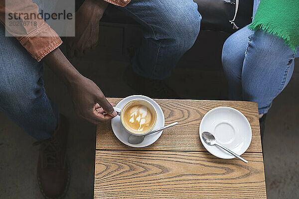 Man sitting with coffee cup near woman at cafe
