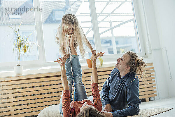 Woman balancing daughter near man at home