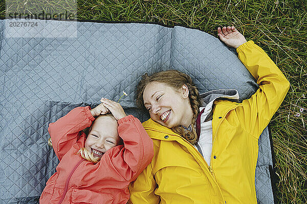 Happy mother and daughter lying on picnic blanket