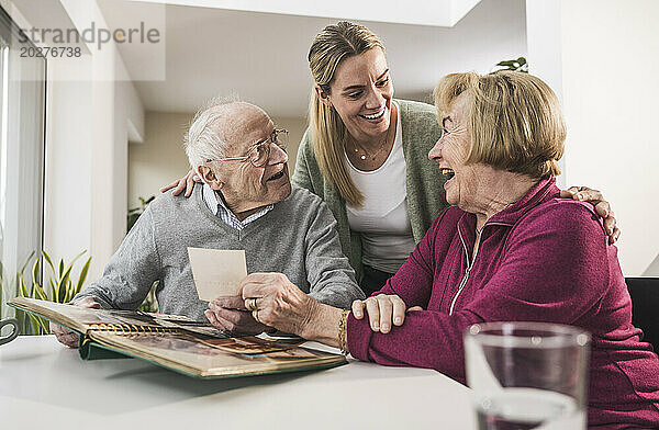 Glückliche häusliche Pflegekraft mit älterem Paar  das ein Foto hält