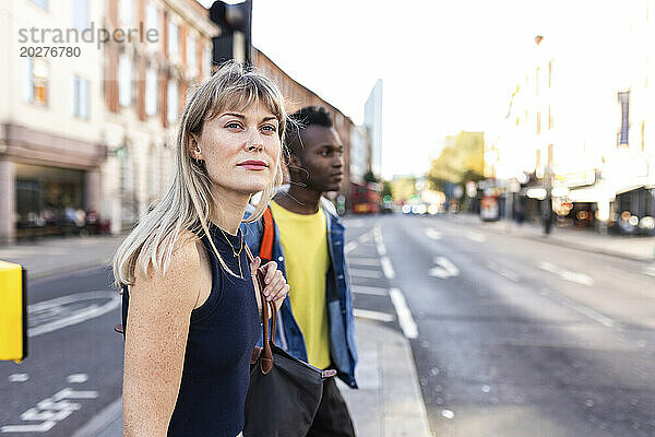 Junge Frau wartet mit Freundin auf der Straße in der Stadt