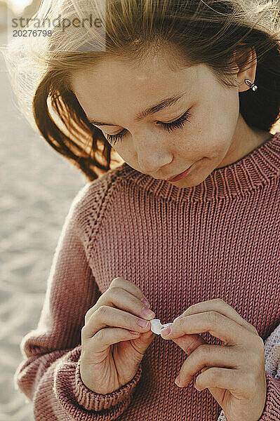 Mädchen trägt Strickpullover am Strand
