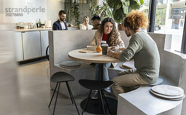 Geschäftskollegen essen zu Mittag und sitzen auf einem Sitzplatz im Bürocafé