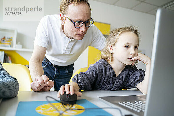 Mädchen benutzt Laptop von Professor im Klassenzimmer