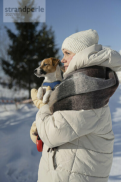 Frau steht mit Hund im Winterpark