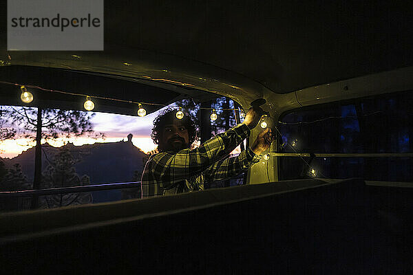 Mann hängt Lichterketten in Lieferwagen