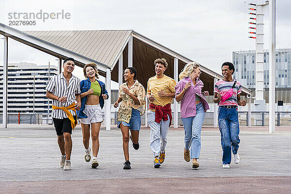 Vielfältige Gruppe junger Freunde mit farbenfroher Kleidung  die gemeinsam Spaß beim Laufen im Freien haben