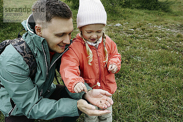 Lächelnder Vater zeigt seiner Tochter Käfer und Blume