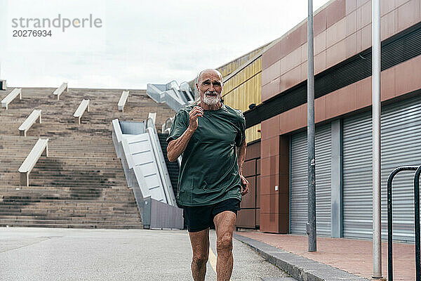 Entschlossener älterer Mann joggt auf Fußweg