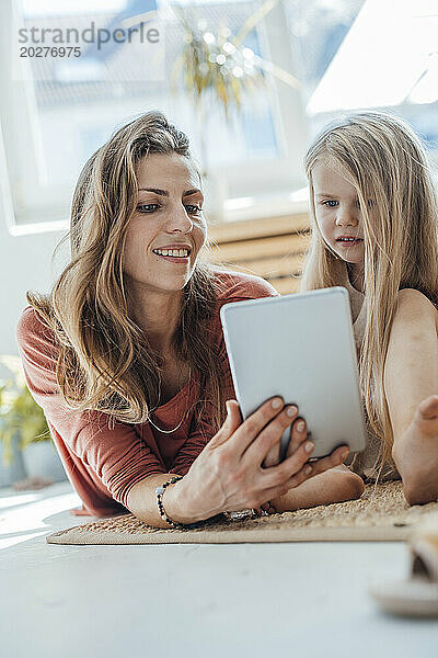 Lächelnde Mutter nutzt Tablet-PC mit Tochter zu Hause