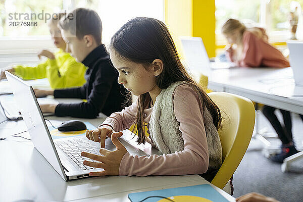 Mädchen benutzt Laptop zum Programmieren im Klassenzimmer