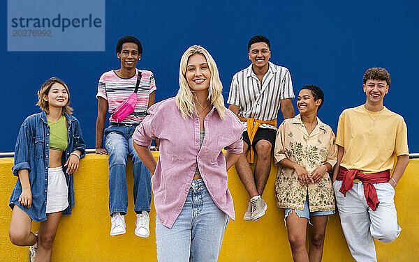 Confident blond woman standing in front of group of friends with hands on hips