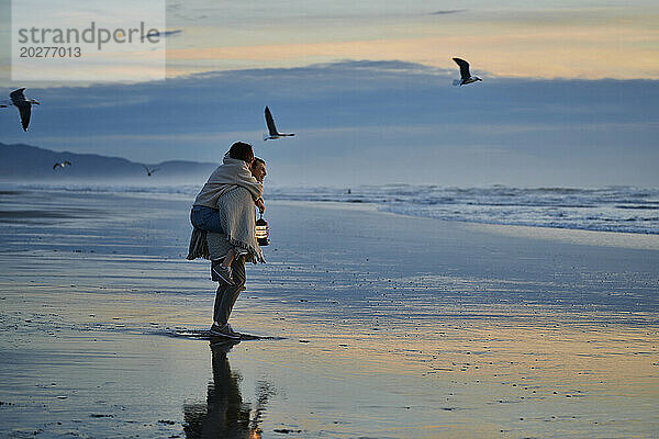 Junges Paar verbringt gemütlichen Sonnenuntergang am Meeresstrand