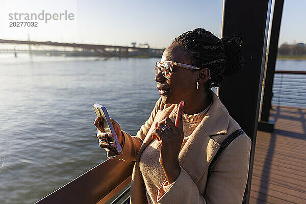 Frau spricht per Videoanruf über Smartphone in der Nähe des Flusses