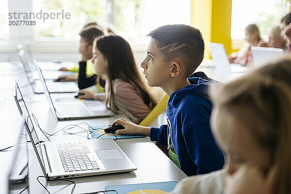 Engagierter Junge benutzt Laptop und lernt im Klassenzimmer Computerprogrammierung