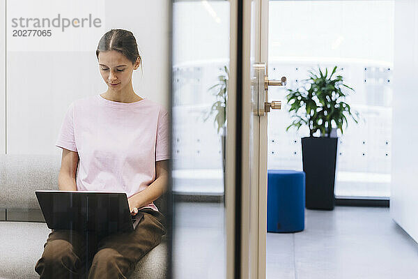 Junge Geschäftsfrau arbeitet im Büro am Laptop