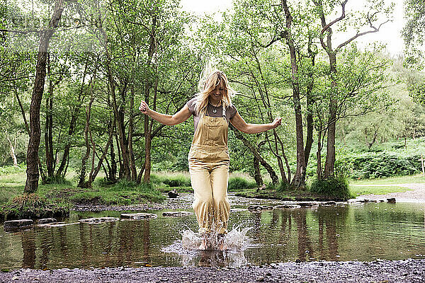 Fröhliche Frau springt in den Fluss