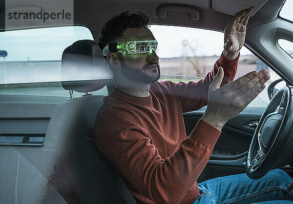 Mann mit grüner Smart-Brille gestikuliert im Auto