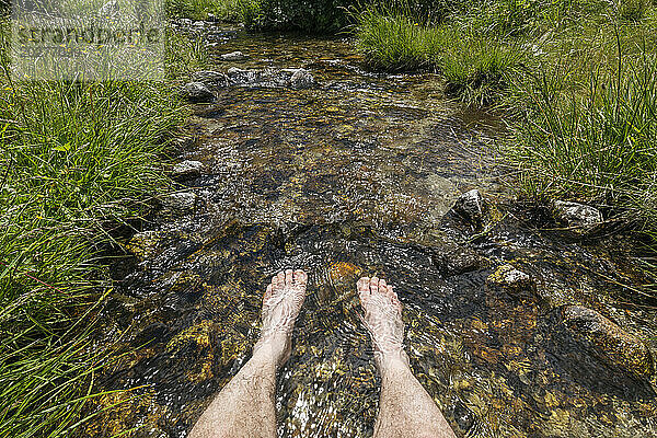 Switzerland  Valais Canton  Man dipping feet in clear stream