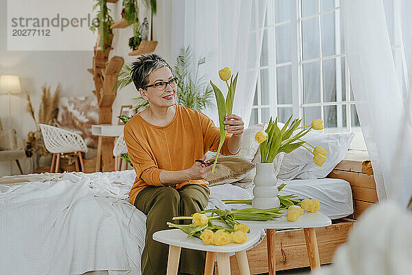 Lächelnde Frau  die zu Hause Tulpen schneidet