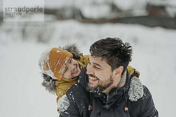 Glücklicher Mann  der im Winter Spaß mit seinem Sohn im Schnee hat