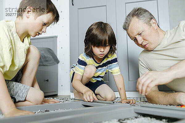Father assisting sons assembling nightstand at home