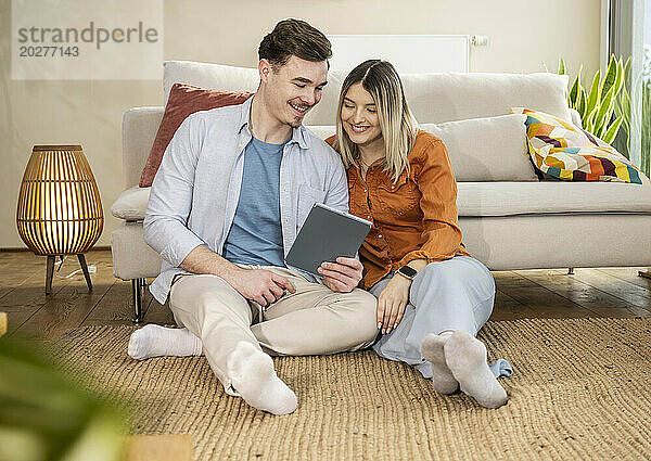 Happy couple using tablet PC in living room at home