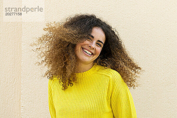 Happy woman tossing hair in front of wall