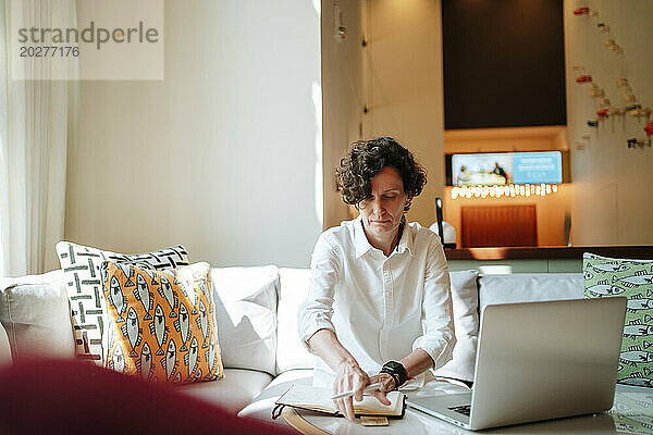 Geschäftsfrau mit Tagebuch und Laptop arbeitet in der Hotellobby