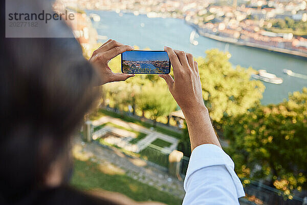 Mann fotografiert den Fluss Douro mit einem Smartphone in der Stadt Porto in Portugal