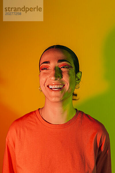 Glückliche junge Frau in Neonbeleuchtung vor Hintergrund mit Farbverlauf
