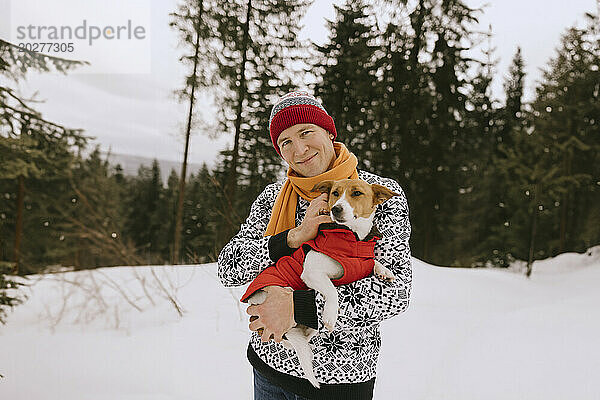 Smiling man with pet dog in winter forest