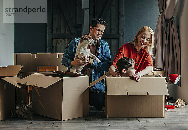 Glückliche Eltern mit ihrem Sohn  der zu Hause im Karton sitzt