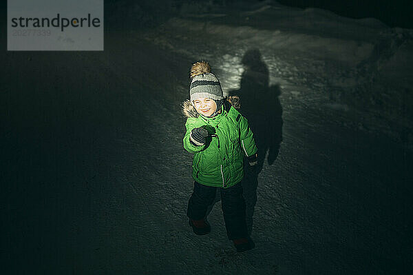 Playful boy standing on snow at night