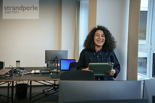 Glückliche Geschäftsfrau hält Tablet-PC im Büro