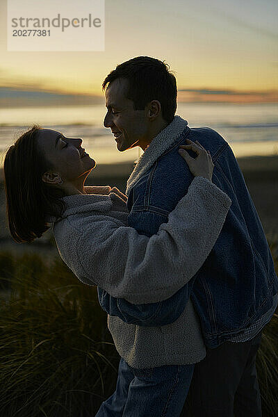 Smiling man and woman doing romantic dance at ocean beach