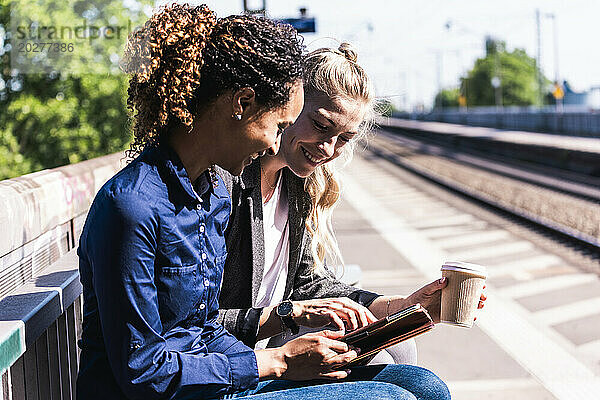 Zufriedene Kollegen nutzen Tablet-PC am Bahnsteig