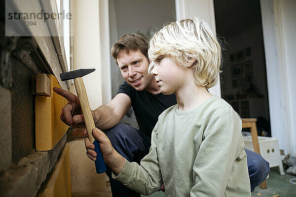 Vater bringt Jungen bei  zu Hause Isolierung an Wand anzubringen