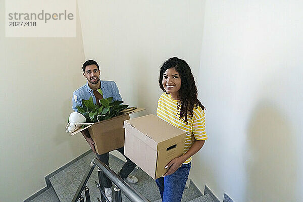 Glückliches Paar trägt Kisten auf der Treppe im neuen Zuhause