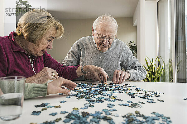Heimbetreuer spielt Puzzlespiel mit älterem Paar