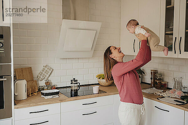 Glückliche Frau  die mit ihrem kleinen Mädchen in der Küche spielt