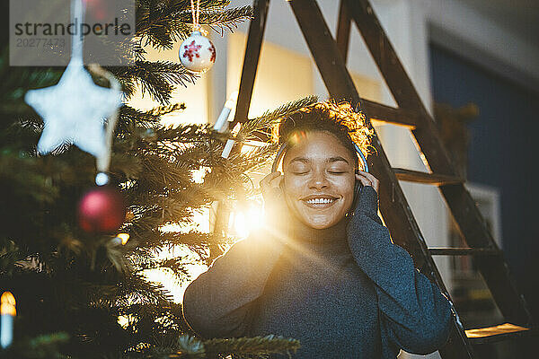 Junge Frau mit Kopfhörern am Weihnachtsbaum