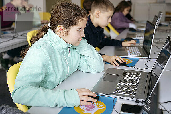 Engagiertes Mädchen nutzt Laptop und lernt Computerprogrammierung am Schreibtisch im Schulklassenzimmer