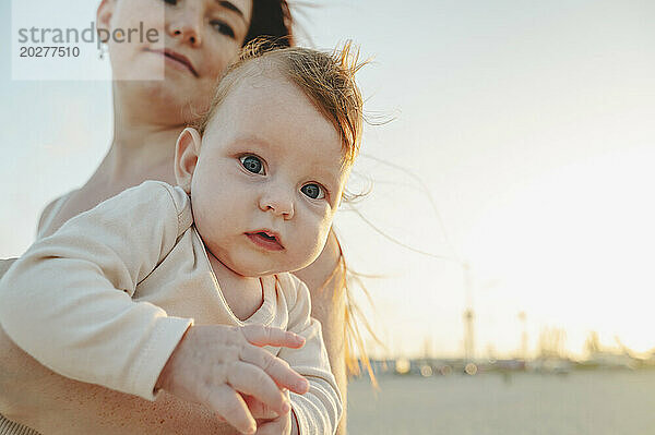 Süßes Babymädchen mit Mutter bei Sonnenuntergang