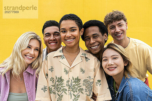 Porträt lachender multiethnischer Freunde vor gelber Wand